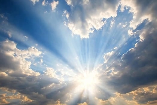 Sunbeams shining through clouds in a blue sky photo
