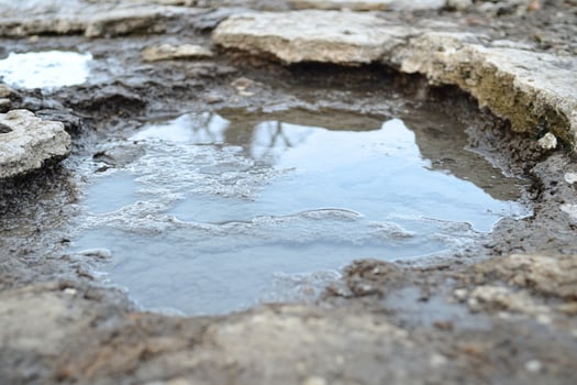 A puddle of water is shown in the dirt photo