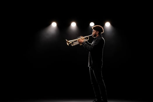 A man in black is playing a trumpet in front of spotlights photo