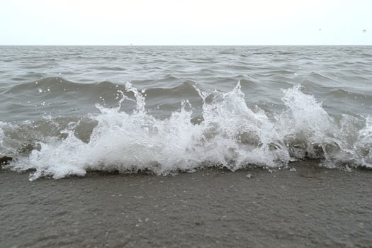 A wave crashing into the shore on a beach photo