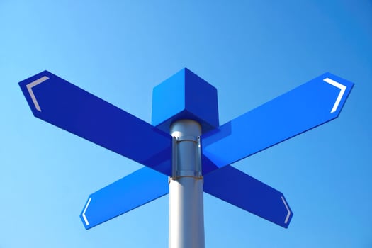 A blue signpost with arrows pointing in different directions, against a blue sky. photo