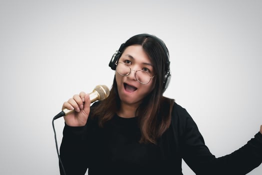 A woman with headphones and a microphone singing into a microphone photo