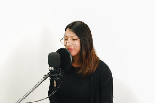 A woman in glasses singing into a microphone photo
