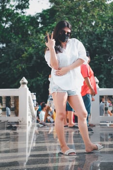A woman in a white shirt and shorts is making a peace sign photo