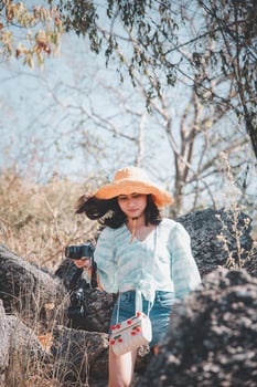 A woman in a hat and blue shirt holding a camera photo