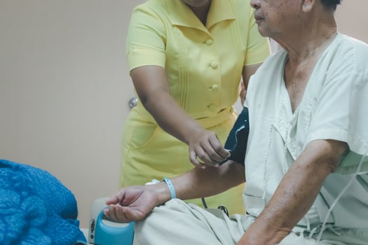 A nurse checking the blood pressure of an elderly man photo