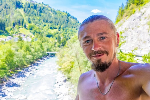 Man takes photo selfie on bridge by river in Fliess Austria.