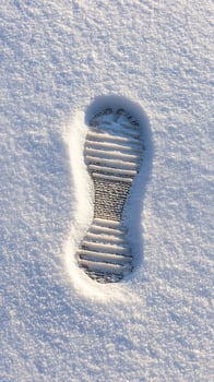 Single Footprint Imprinted on Sparkling Winter Snow. photo
