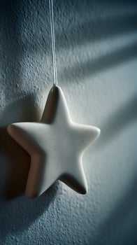 Minimalist Star Ornament Hanging with Soft Shadows on Textured Wall. photo