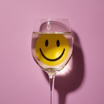Happy Face Floating In Wine Glass On Pink Background. photo