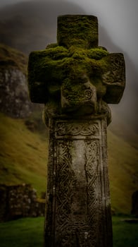 Ancient Celtic Cross Covered in Moss Amidst Misty Scottish Highlands. photo