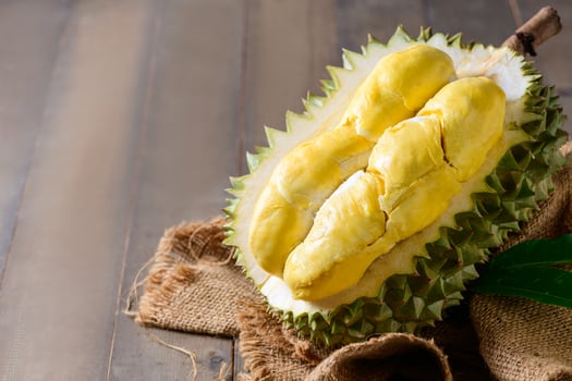 Ripe durian fruit or Durio zibethinus with yellow creamy pulp exposed, isolated on white background. photo