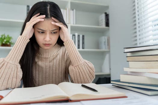 Asian student woman have anxiety because of exams, female prepare for test and learning lessons in the library. stress, despair, haste, misunderstanding reading, discouraged, expectation,. photo