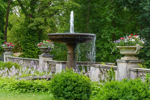 A fountain in a garden with flowers and trees photo