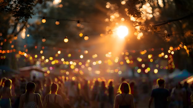 Crowd enjoying outdoor music festival at sunset with string lights photo