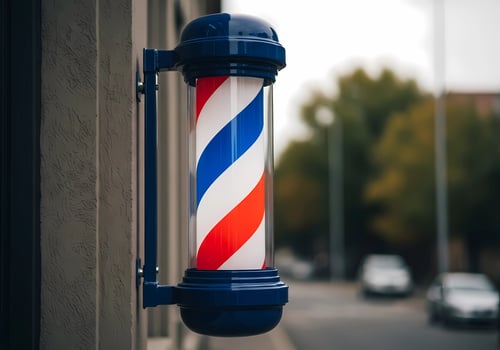 A barber pole with red white and blue stripes outside on a building wall photo