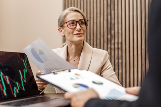 Businesswoman with glasses is discussing financial reports and charts with a colleague in a modern office, showcasing strategic planning and collaboration in a professional setting photo