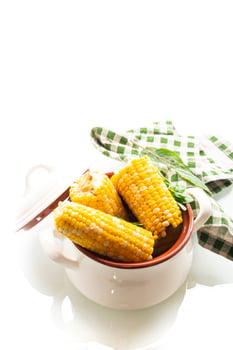 Two boiled corn cobs with dill on a white background photo