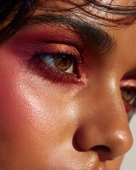 Artistic close up of Indian beauty cheek featuring ombre blush blend in ruby red, golden shimmer, burnt orange, and deep rose on luminous brown skin photo