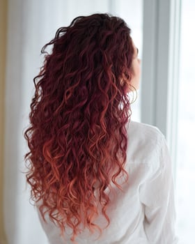 Stylish ombre curls seen from behind featuring deep burgundy at the top fading to cherry red and ending in delicate soft coral tones photo