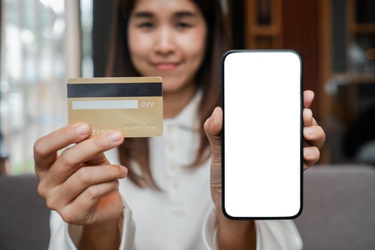 Close-up of a woman displaying a credit card and a smartphone with a blank screen, symbolizing online shopping or digital payment. photo