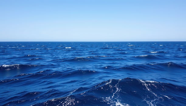 Vast Blue Ocean Waves Under Clear Blue Sky with Gentle Ripples and Calm Water Surface photo