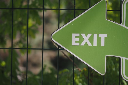 Green exit sign pointing left towards the pathway photo