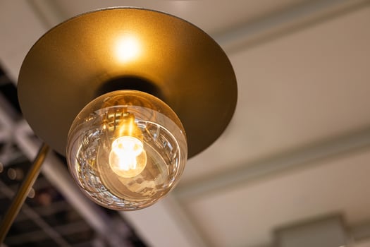 Vintage Light Bulb with Warm Glow in Modern Fixture. a glowing vintage-style Edison bulb encased in a modern metal lamp fixture. interior decor, lighting design, energy, and cozy atmospheres. photo