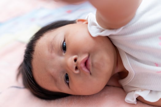 Newborn asian baby captured playfully in cozy home environment close-up perspective photo