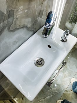 A welldesigned bathroom features a strategically placed sink with a functional faucet and a properly sized mirror above, enhancing convenience for daily use and grooming photo