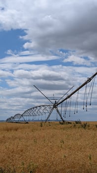 An Irrigation System Over Crop Fields, Set Beneath a Beautiful, Cloudy Sky Above photo