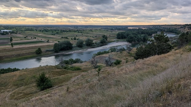 A Serene Landscape at Dusk featuring a River and Gentle Rolling Hills in the background photo