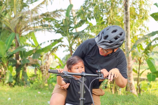 Picture of father and son riding a bicycle on the road photo