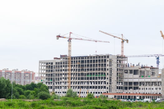Moscow, Russia, 18.06.2025 Large building under construction with multiple tower cranes against a white sky. New city block developing. photo