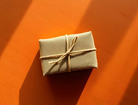 A small gift wrapped in brown paper on a wooden table photo