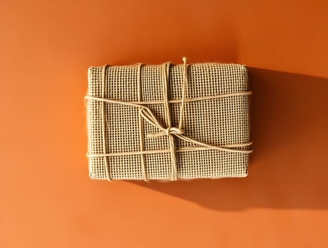 A wrapped gift wrapped in twine on an orange background photo