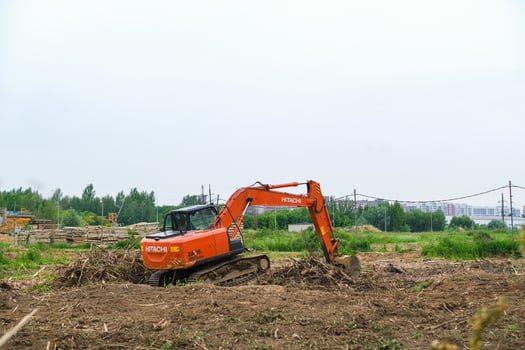 Moscow, Russia, 18.06.2025 Orange excavator machine working on a construction site, clearing land with its bucket. Heavy machinery for ground works and building development. photo