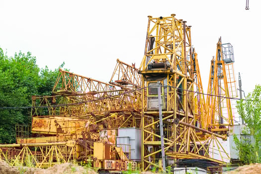 Moscow, Russia, 18.06.2025 Yellow construction cranes and industrial machinery sit abandoned outdoors. Old rusty metal structures from a building site for heavy lifting. photo