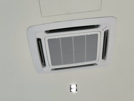 Ceiling cassette air conditioner unit providing cooling and comfort. modern HVAC system with ventilation for optimal climate control in an office or home interior environment photo