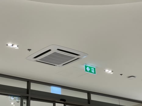 Modern ceiling with air conditioner ventilation system. green emergency exit sign provides sense of safety next to an interior light. clean and functional design photo
