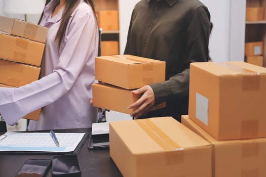 Two people are holding boxes in an office photo