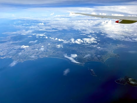 A panoramic aerial view of coastline and islands, taken from a plane. The sea, sky, and land blend seamlessly under gentle clouds. Scenic or business flight travel photo. Nature background. photo