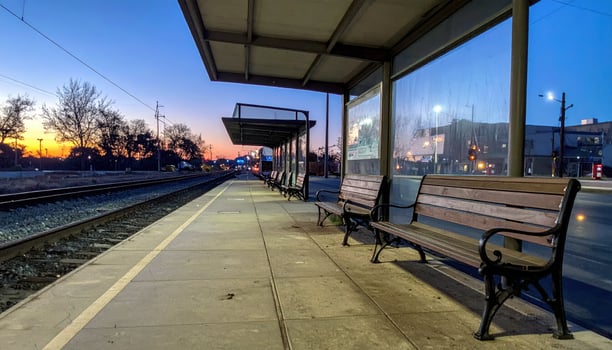 A train station with a bench and a train photo