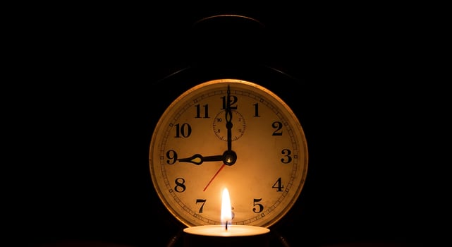 Candlelight illuminates vintage clock face in darkness photo