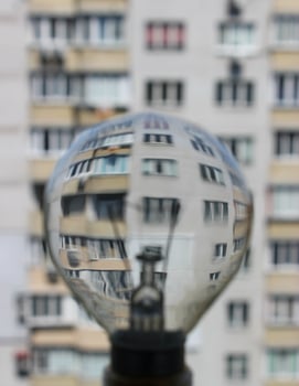 Blurred electric light bulb as a magnifying glass in which the facade of an apartment building is visible photo