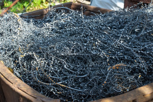 Shiny chips after metal processing on a milling and grinding machine are thrown into a rusty container for the collection of industrial waste. High quality photo