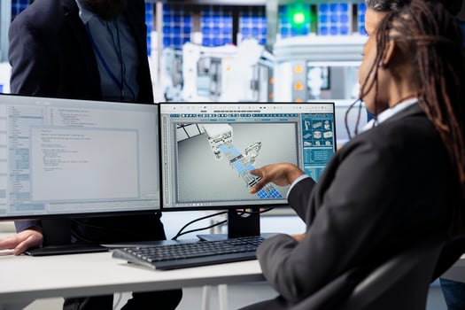 Programmer in photovoltaics factory office using PC to update software of robot arms placing solar panels on assembly lines, communicating changes to team leader, close up shot photo