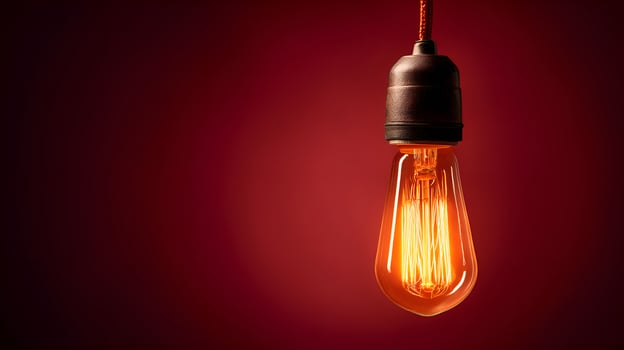 Glowing light bulb hanging on red background symbolizing ideas and innovation photo