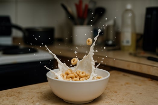 Dynamic Cereal Milk Splash in White Bowl on Kitchen Counter with Background Utensils photo