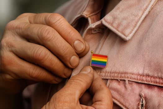 Hand Pinning Rainbow Flag Pin on Jacket Symbolizing LGBTQ Pride and Support in Close-Up View with Detailed Texture Capturing Inclusivity and Diversity photo